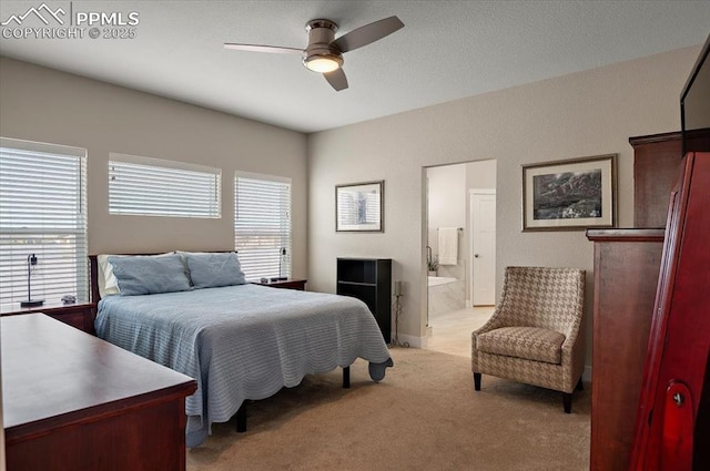 bedroom featuring light colored carpet, ensuite bathroom, and a ceiling fan