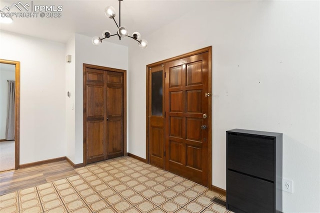 entrance foyer featuring an inviting chandelier, light floors, and baseboards