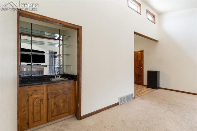 bar with visible vents, light carpet, baseboards, indoor wet bar, and a sink