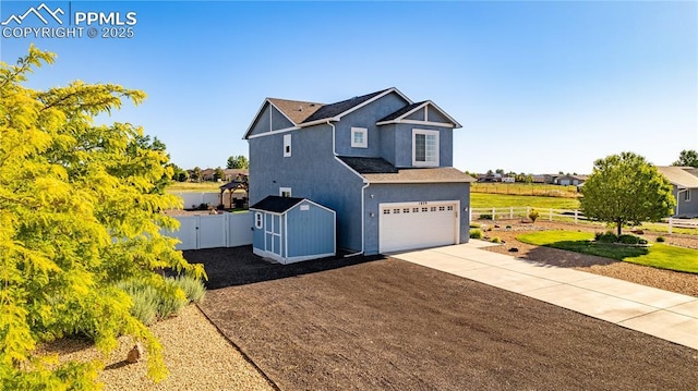 view of front of house with concrete driveway, stucco siding, a shed, fence, and a garage