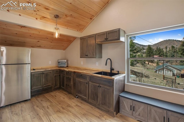 kitchen featuring a sink, plenty of natural light, freestanding refrigerator, vaulted ceiling, and wood ceiling