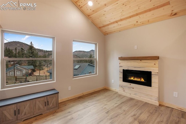 unfurnished living room featuring a glass covered fireplace, high vaulted ceiling, wood ceiling, a mountain view, and light wood finished floors