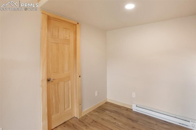 unfurnished room featuring wood finished floors, recessed lighting, baseboards, and a baseboard heating unit