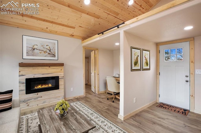 foyer entrance with a glass covered fireplace, baseboards, recessed lighting, and wood finished floors