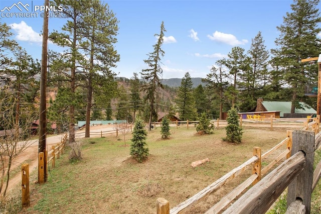 view of yard with a view of trees, fence, and a mountain view