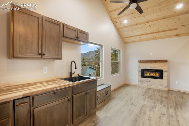 kitchen with ceiling fan, a sink, wooden ceiling, light wood finished floors, and butcher block countertops