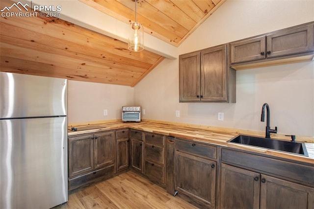 kitchen featuring a sink, wood counters, freestanding refrigerator, vaulted ceiling with beams, and wood ceiling