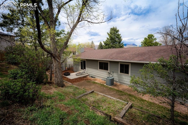 rear view of property featuring a patio, a shingled roof, and central AC unit