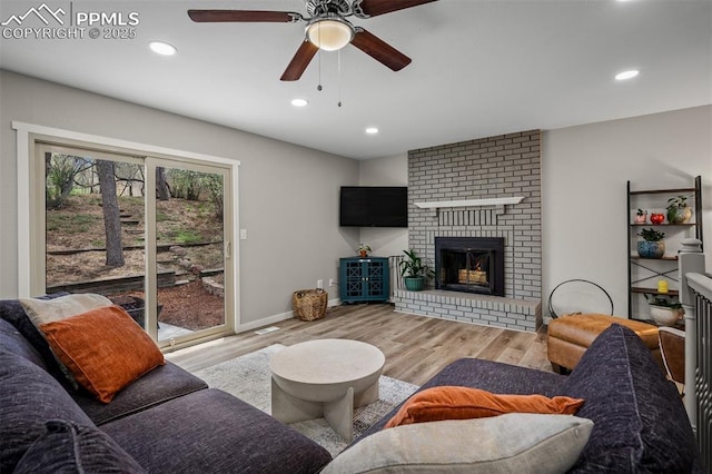 living area featuring a brick fireplace, recessed lighting, ceiling fan, and wood finished floors