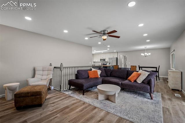 living area featuring recessed lighting, wood finished floors, and ceiling fan with notable chandelier