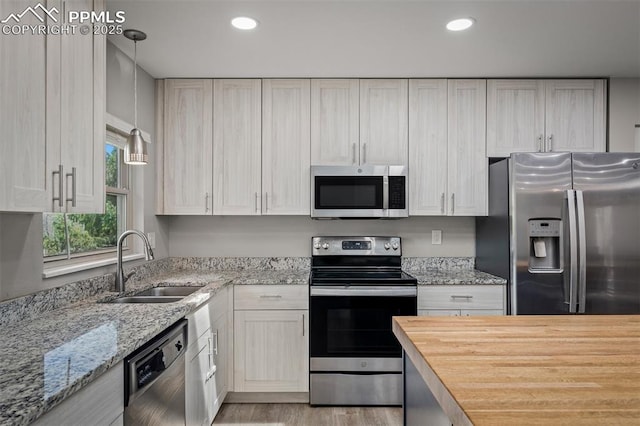 kitchen featuring recessed lighting, a sink, light wood-style flooring, hanging light fixtures, and appliances with stainless steel finishes