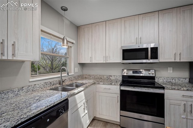 kitchen featuring stainless steel appliances, light stone counters, and a sink