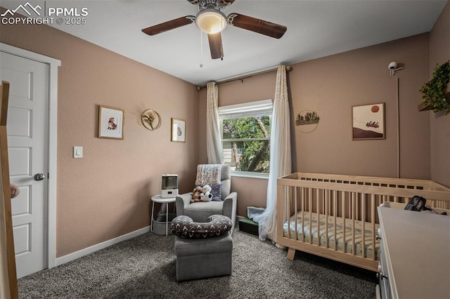 bedroom featuring baseboards, a nursery area, a ceiling fan, and carpet flooring