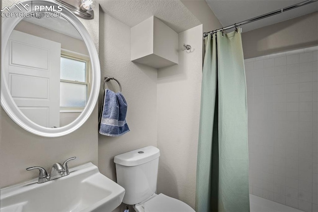 full bathroom with tiled shower, toilet, and a sink