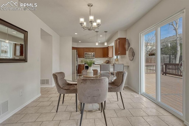 dining area with baseboards, visible vents, and an inviting chandelier