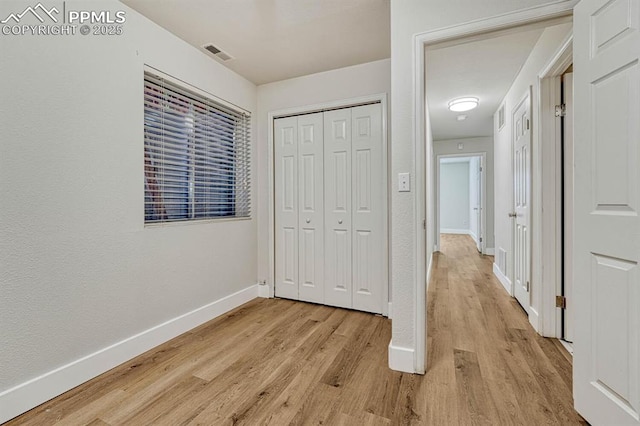 unfurnished bedroom featuring visible vents, a closet, light wood finished floors, and baseboards