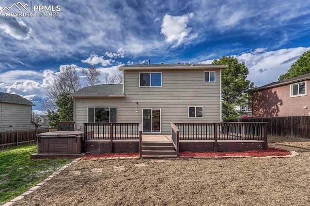 back of property with a wooden deck, a fenced backyard, and a hot tub