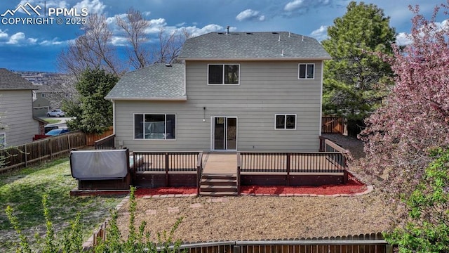 rear view of house with a shingled roof, a wooden deck, and a fenced backyard