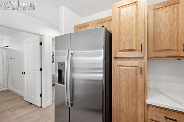 kitchen featuring light brown cabinetry, light wood-style flooring, stainless steel fridge with ice dispenser, and light countertops