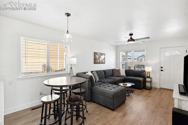 living room with baseboards, ceiling fan, light wood finished floors, and visible vents