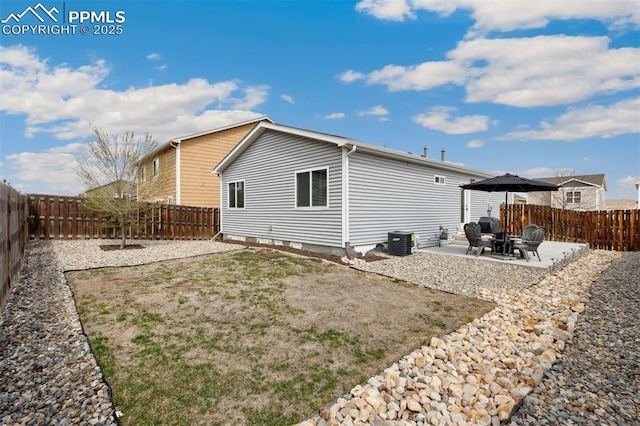 rear view of property featuring a fenced backyard, a patio, and central AC