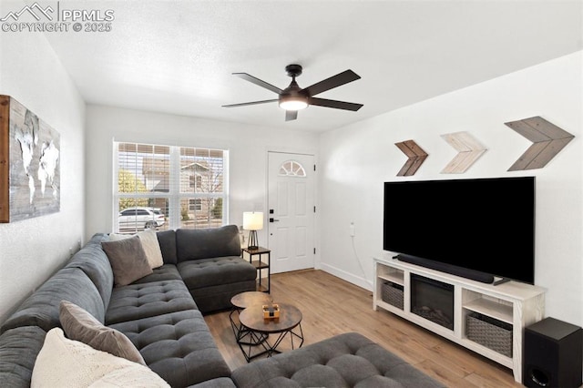 living room with baseboards, ceiling fan, and wood finished floors