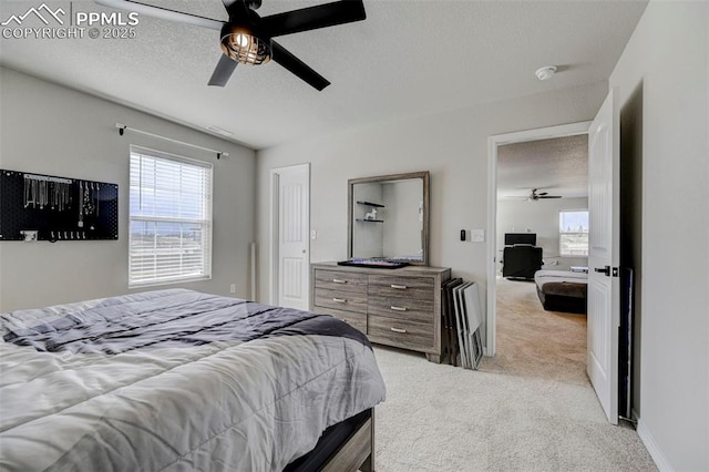 carpeted bedroom with a textured ceiling, ceiling fan, and multiple windows
