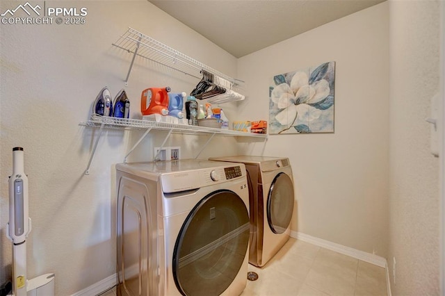 washroom featuring separate washer and dryer, laundry area, light tile patterned floors, and baseboards
