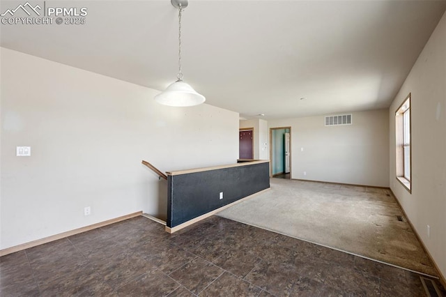 carpeted spare room featuring baseboards, visible vents, and stone finish floor