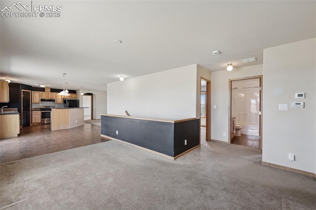 unfurnished living room with dark colored carpet, a sink, visible vents, and baseboards