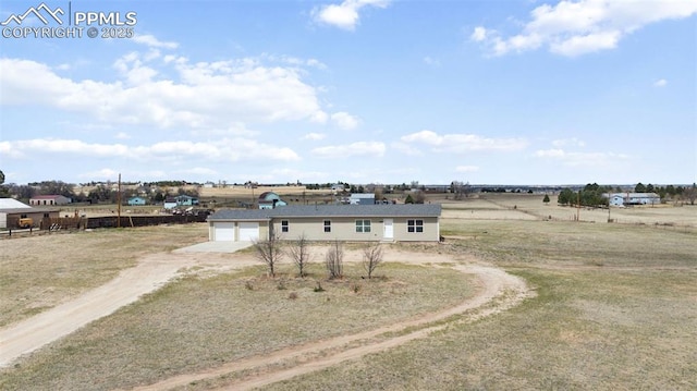 view of front of property with a rural view, dirt driveway, and an attached garage
