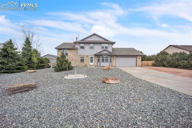 traditional-style home featuring brick siding, driveway, fence, and a garage