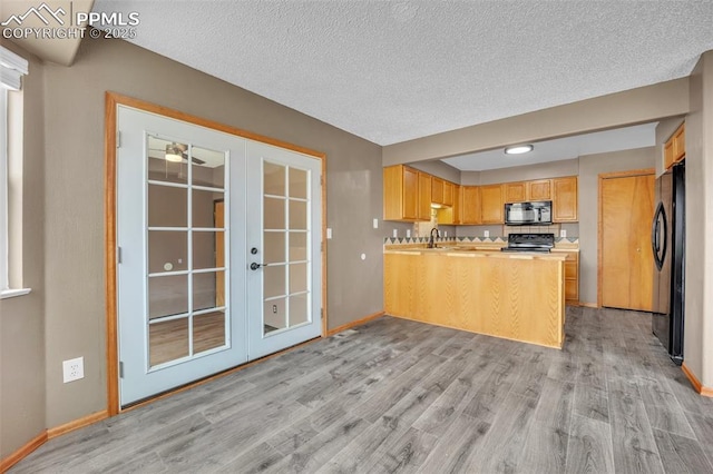 kitchen featuring black appliances, french doors, light wood-style floors, baseboards, and a textured ceiling