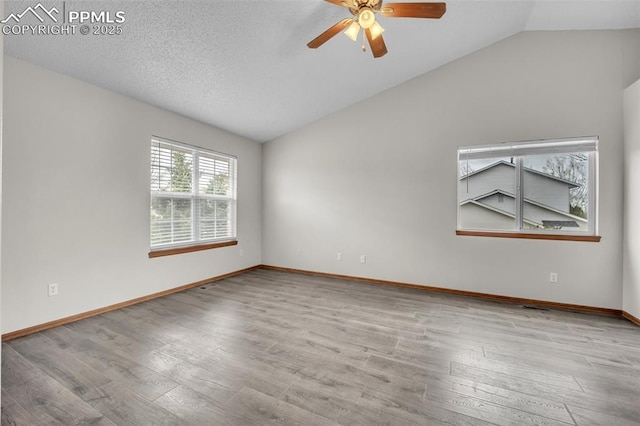 empty room featuring lofted ceiling, a ceiling fan, wood finished floors, and baseboards