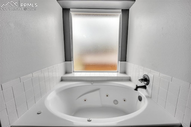 full bathroom with a tub with jets and a textured wall