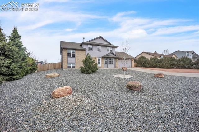traditional-style home with brick siding, fence, an attached garage, and driveway