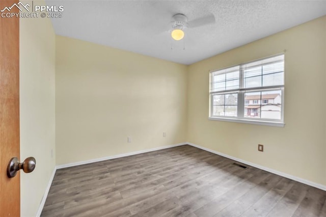 unfurnished room featuring ceiling fan, wood finished floors, baseboards, and a textured ceiling