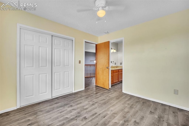 unfurnished bedroom featuring wood finished floors, baseboards, a closet, a sink, and a ceiling fan