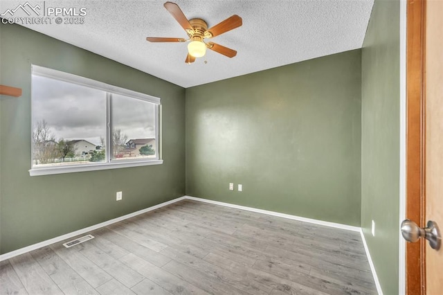 spare room featuring ceiling fan, wood finished floors, a textured ceiling, and baseboards