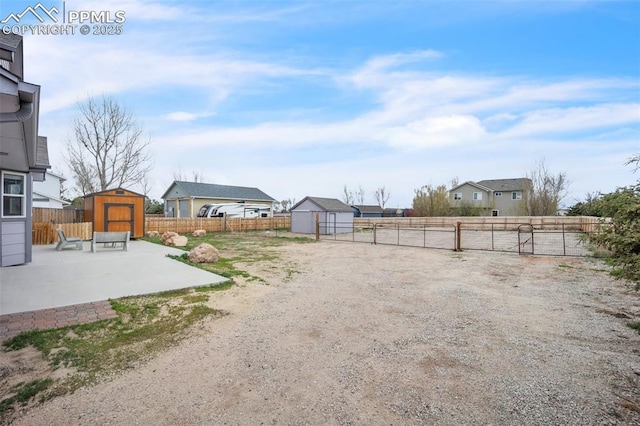 fenced backyard featuring a shed, a patio area, and an outbuilding