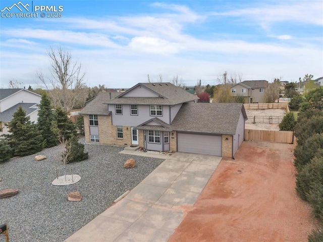 traditional home featuring an attached garage, brick siding, driveway, fence, and roof with shingles