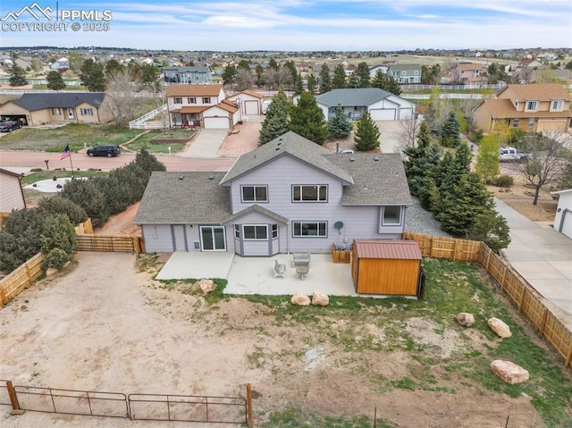 rear view of house with a patio area, a residential view, a fenced backyard, an outdoor structure, and dirt driveway