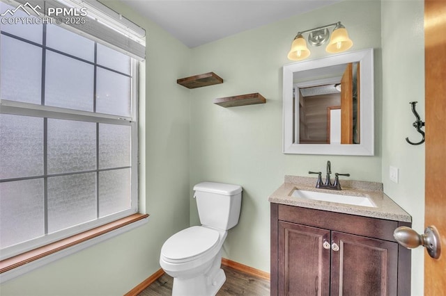 half bath with wood finished floors, toilet, vanity, and baseboards