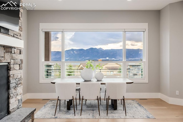 dining area with light wood finished floors, recessed lighting, a fireplace, a mountain view, and baseboards