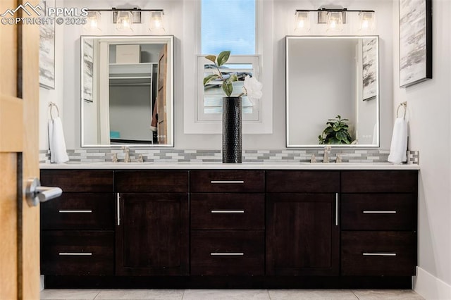 full bathroom with tasteful backsplash, tile patterned flooring, double vanity, and a sink