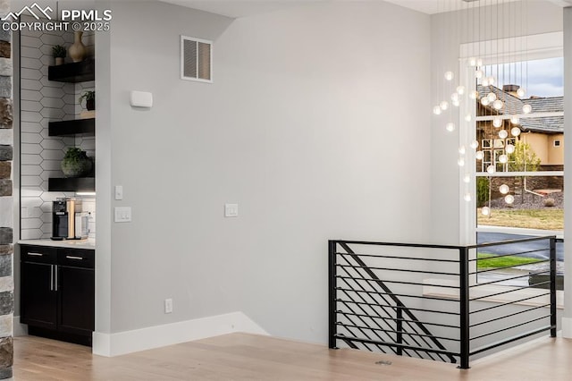 interior space with an upstairs landing, visible vents, light wood-style flooring, and baseboards