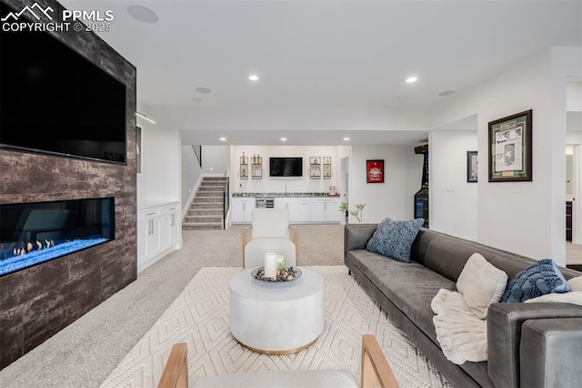 living room with a fireplace, stairway, recessed lighting, and light carpet