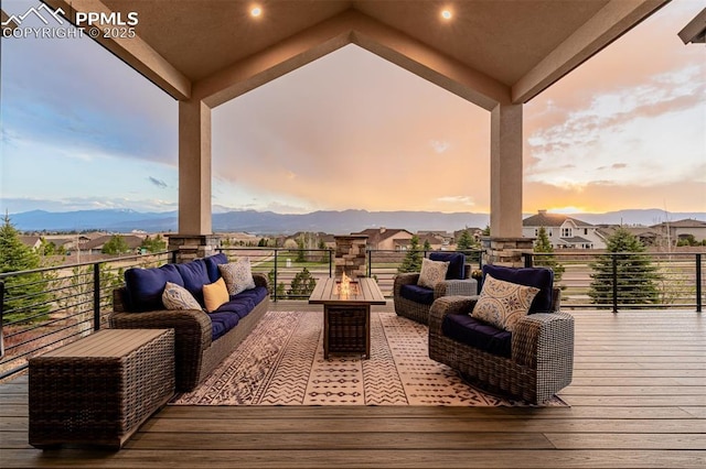 wooden deck with an outdoor living space with a fire pit and a mountain view