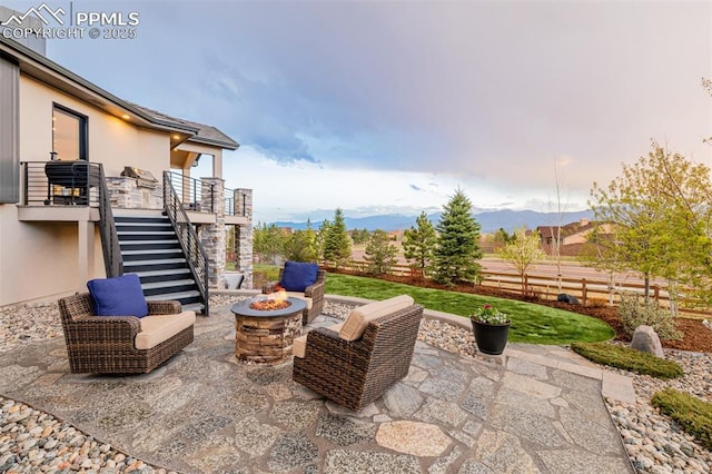 view of patio / terrace featuring fence, a fire pit, stairs, and a mountain view