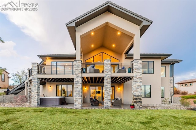 back of property with outdoor lounge area, a hot tub, stucco siding, and a balcony